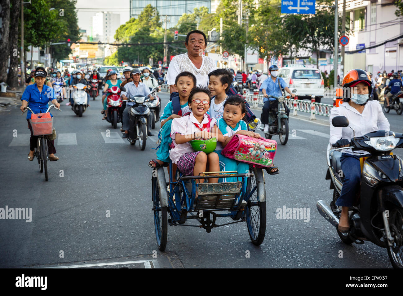 Schule Kinder reiten Fahrradrikscha auf einer belebten Straße, Ho-Chi-Minh-Stadt (Saigon), Vietnam. Stockfoto