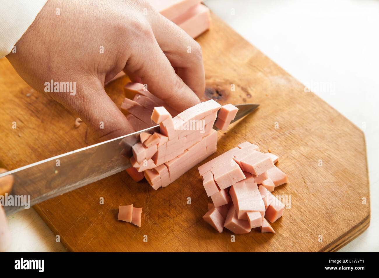 weibliche Hände Closeup Wurst in Würfel schneiden Stockfoto