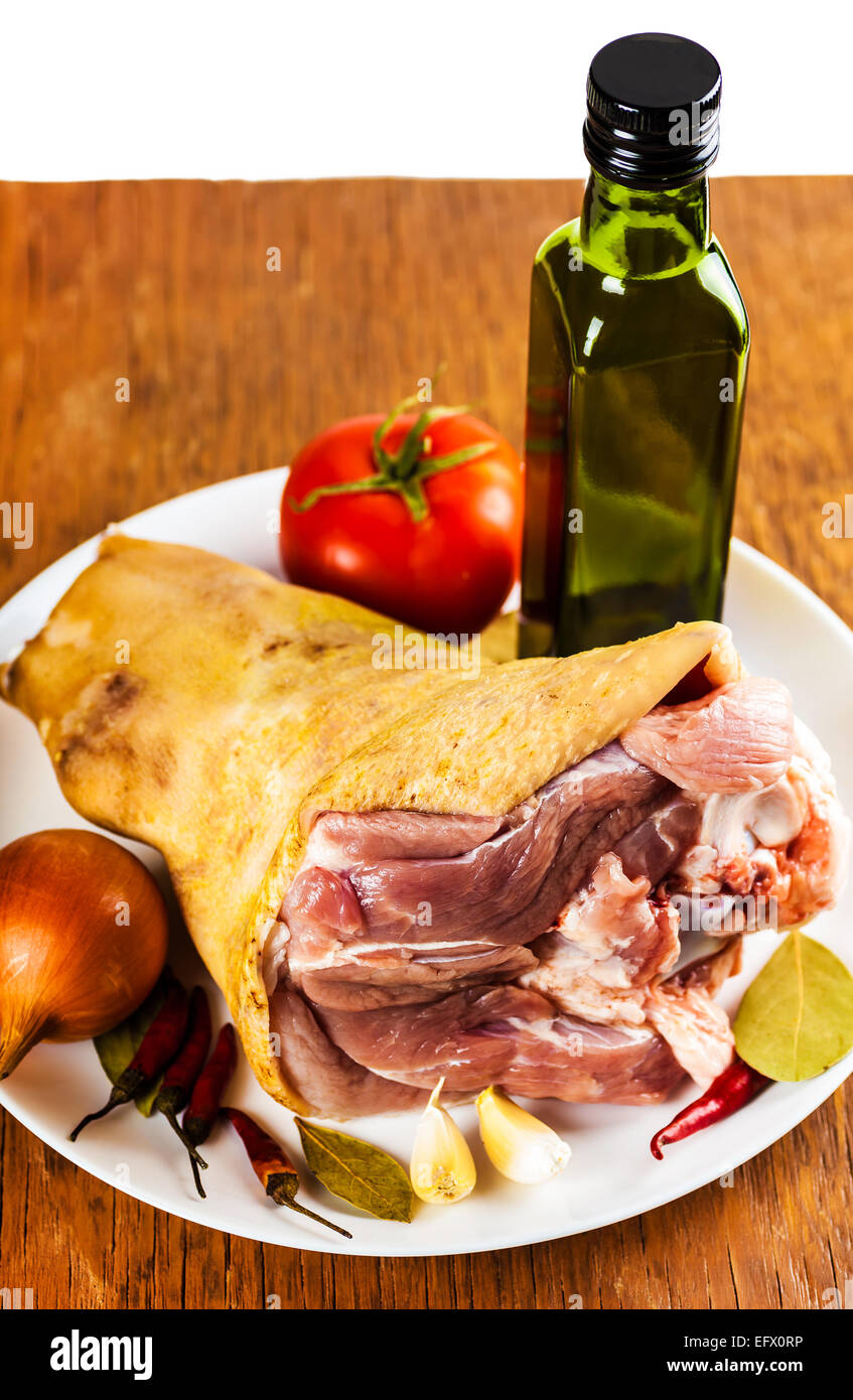 rohes Schweinefleisch Schaft auf einem Teller mit Gewürzen und Gemüse, einen hölzernen Hintergrund Stockfoto