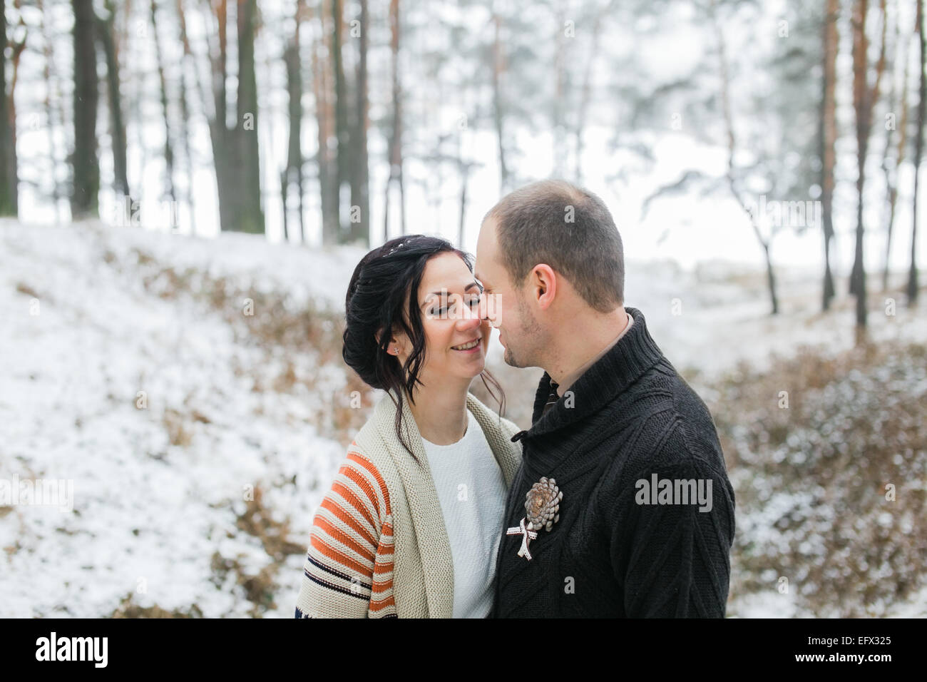 Braut und Bräutigam umarmt im tief verschneiten Winterwald Stockfoto