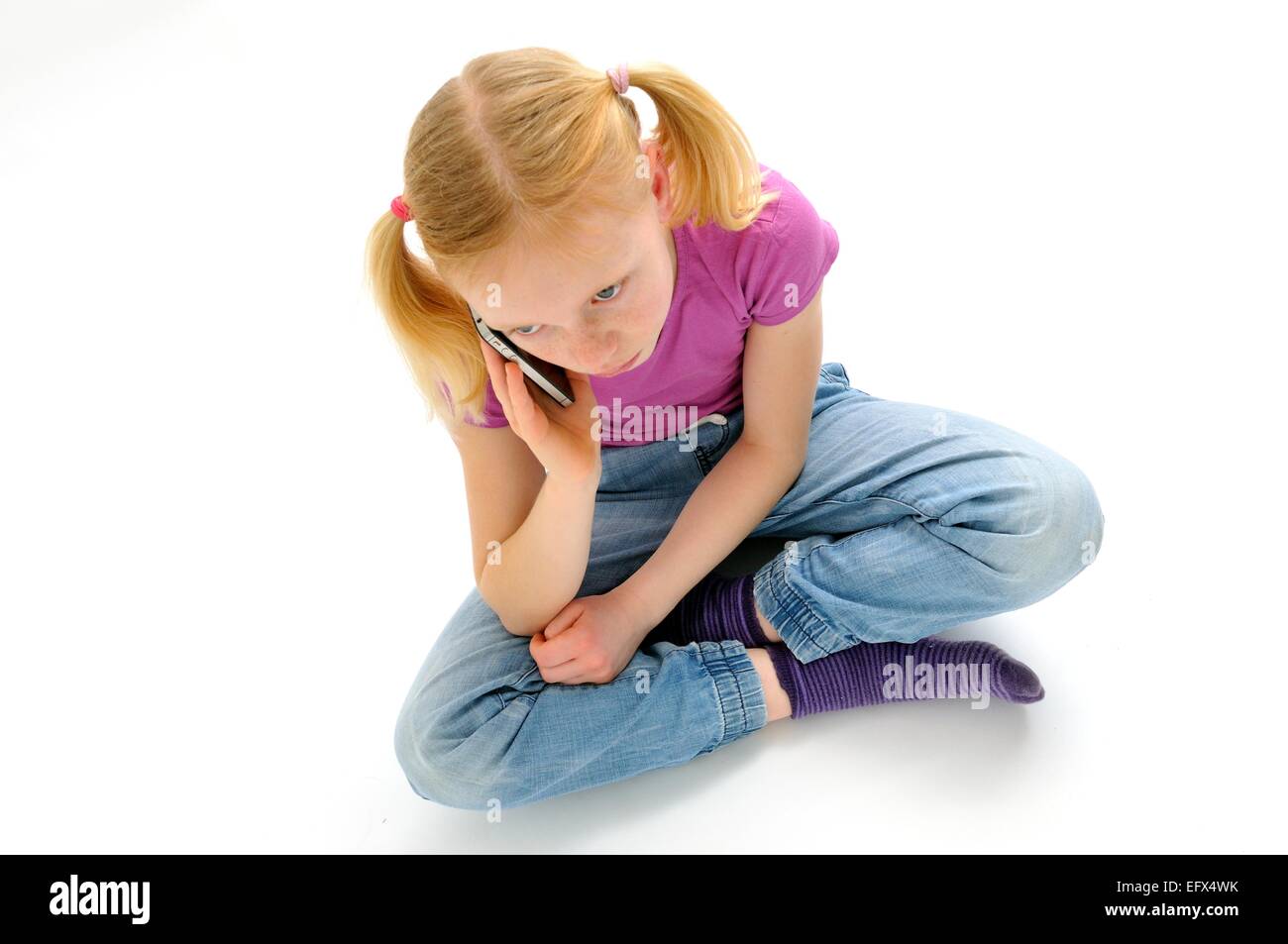 Junges Mädchen Schneidersitz sitzen und reden über Handy Stockfoto
