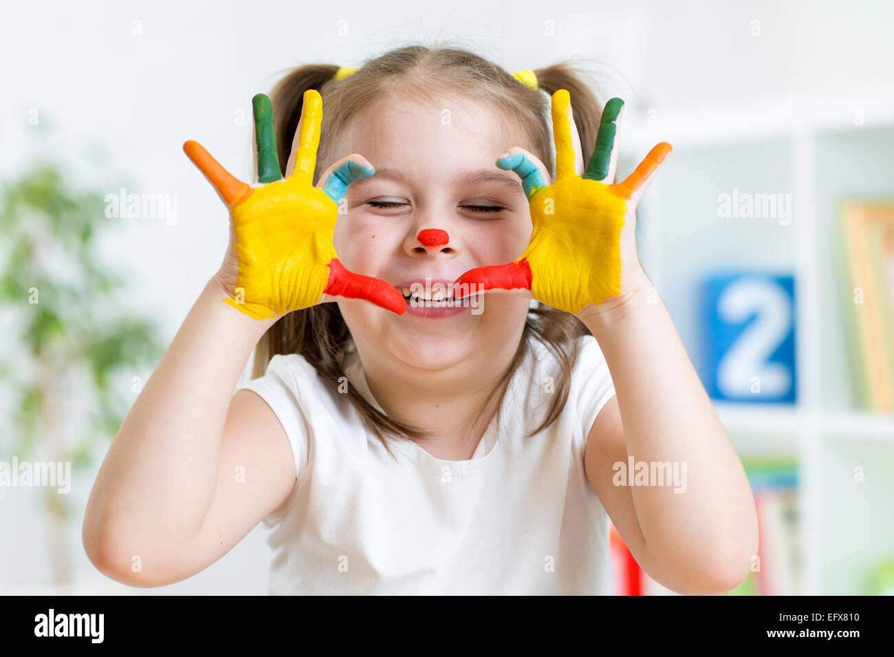 Lustige Kinder-Mädchen spielen mit Farbe malt Stockfoto