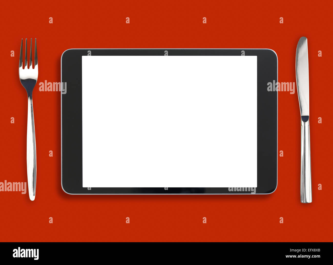iPad auf roten Tisch mit Messer und Gabel Stockfoto