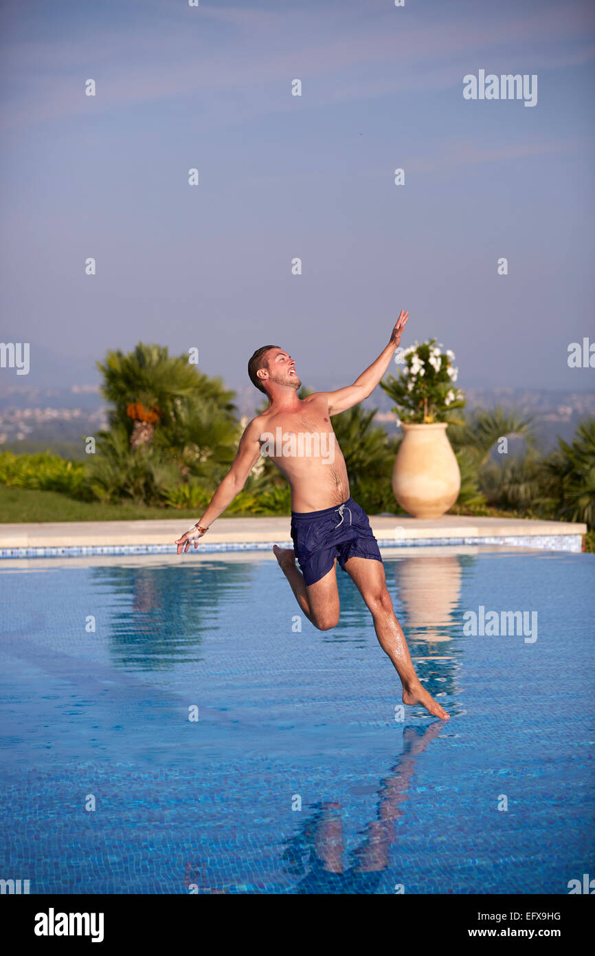 Junger Mann in den Pool springen Stockfoto