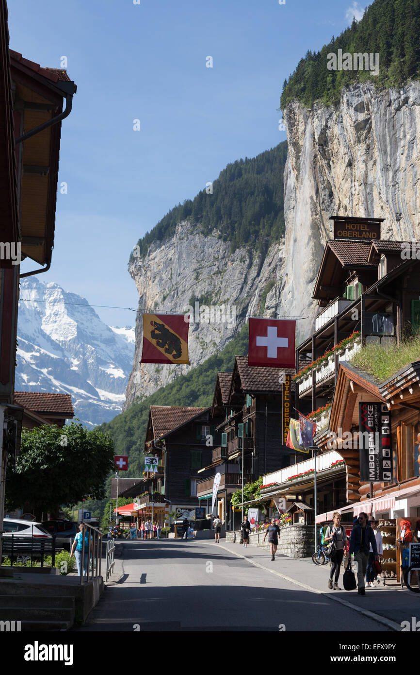Besucher gehen unter Geschäfte und Firmen, die Straßen in der Gemeinde Lauterbrunnen in den Schweizer Alpen säumen Stockfoto