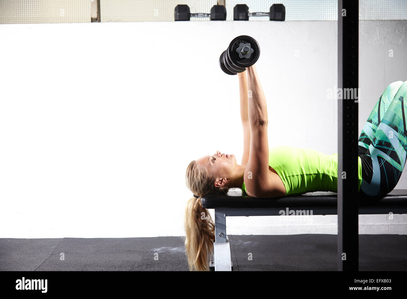 Junge Frau liegt auf Trainingsbank heben bar Glocke im Fitness-Studio Stockfoto