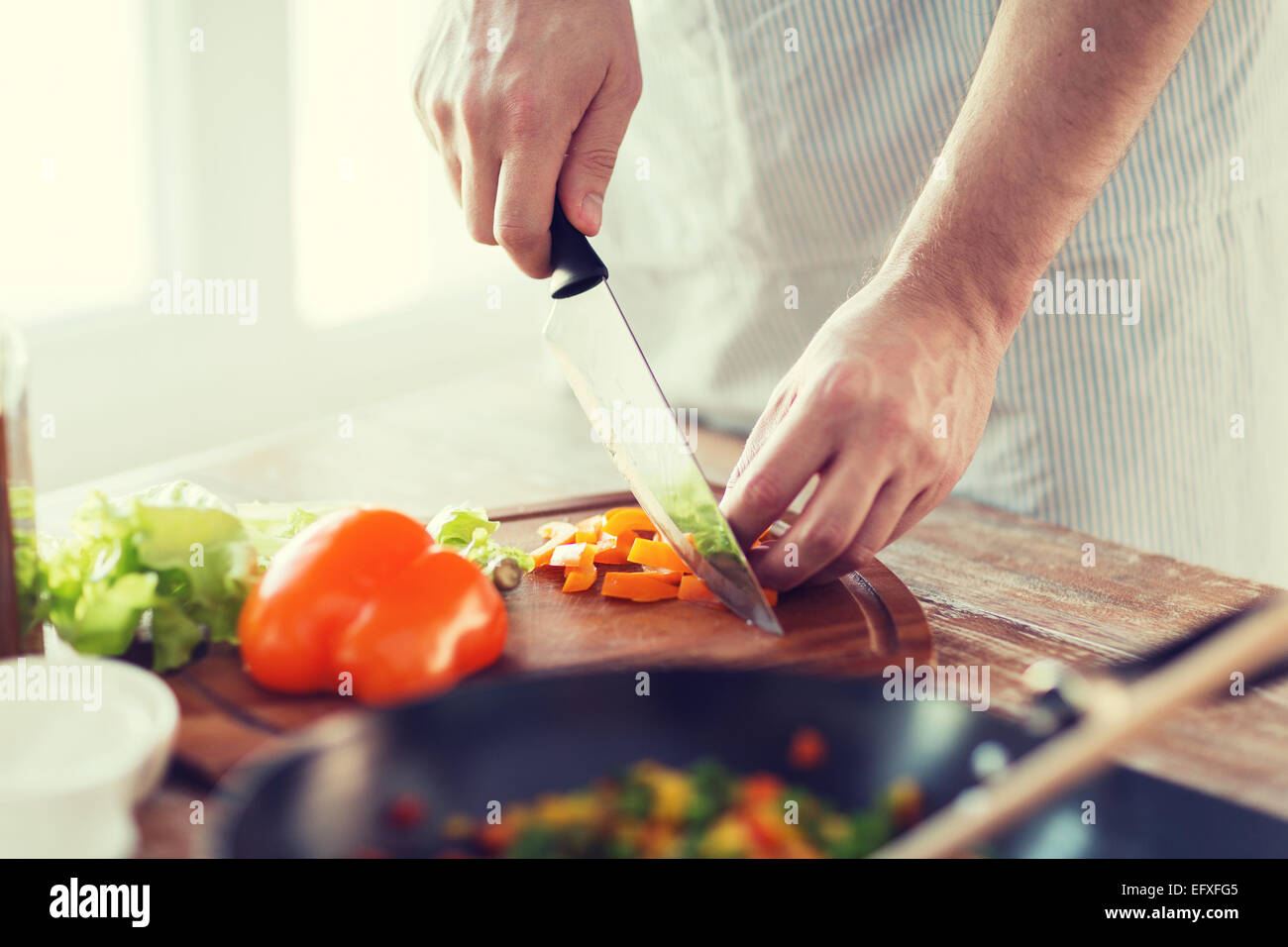 Nahaufnahme eines männlichen Hand schneiden Paprika an Bord Stockfoto