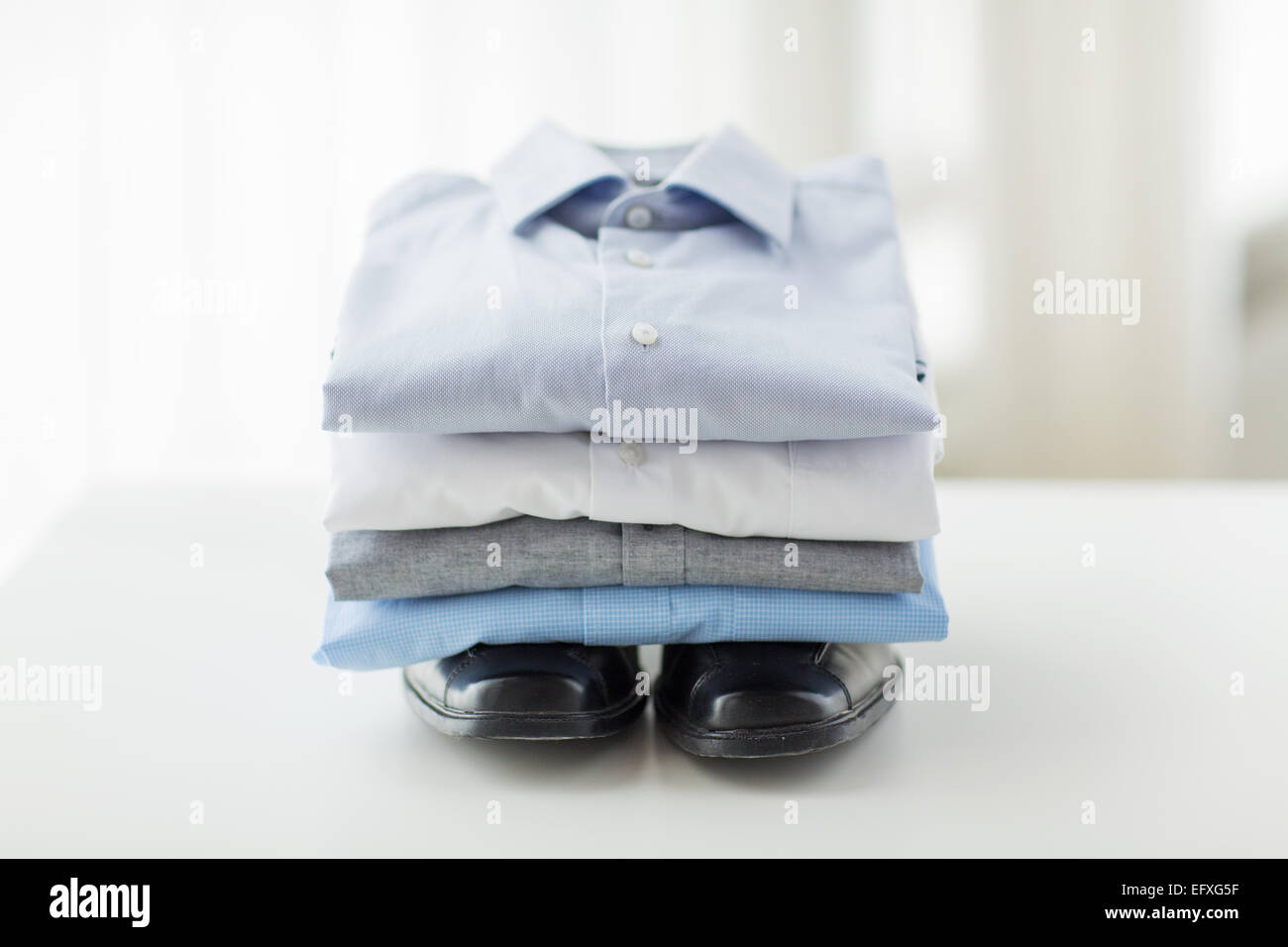 Nahaufnahme eines gefalteten männlichen t-Shirts und Schuhe auf Tisch Stockfoto