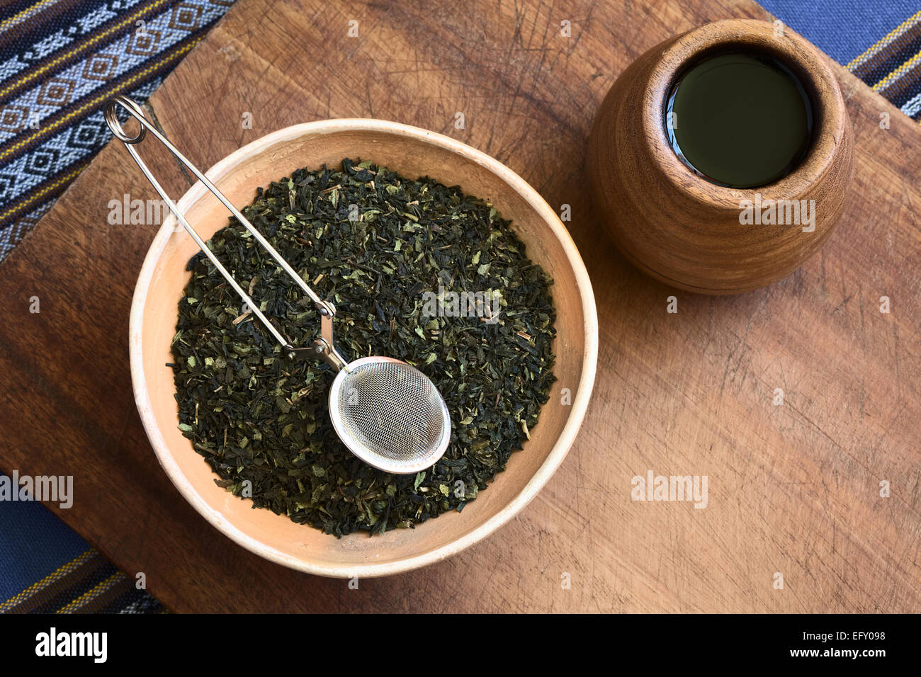 Overhead Schuss von getrockneten grünen Teeblätter in Schüssel mit einem Teesieb auf Top und hölzernen Teetasse auf der Seite Stockfoto