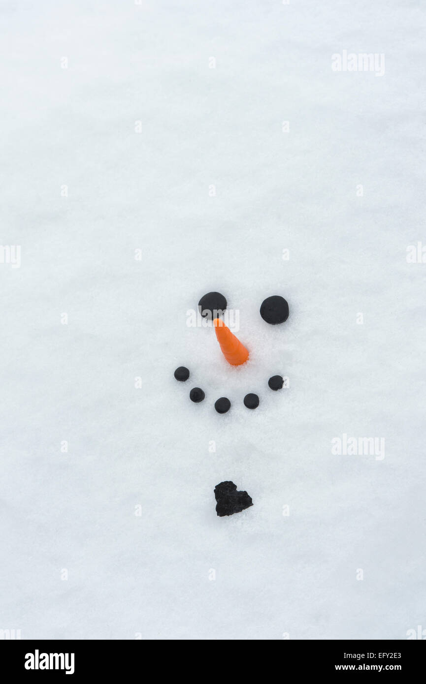 Glücklich Schneemann Gesicht mit einem großen Kohle-Herz im Schnee Stockfoto