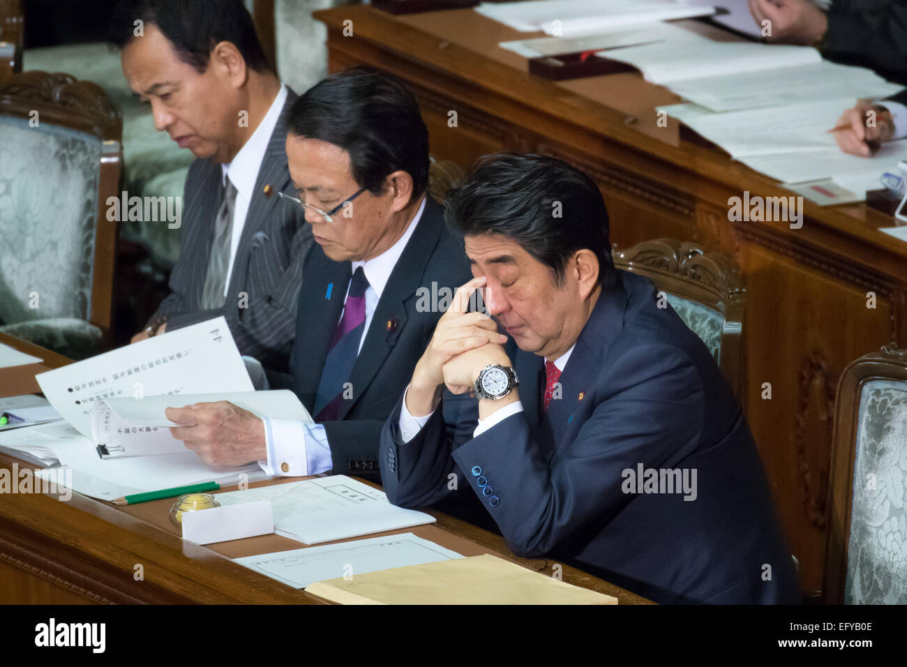 Tokio, Japan. 12. Februar 2014. Japans Ministerpräsident Shinzo Abe berührt als er Außenminister Fumio Kishida hört sein Augenlid liefert seine außenpolitische Rede während einer Plenarsitzung der beiden Häuser des Reichstages in Tokio auf Donnerstag, 12. Februar 2015. Außenminister Taro Aso prüft seine Papiere neben Abe. Bildnachweis: AFLO/Alamy Live-Nachrichten Stockfoto