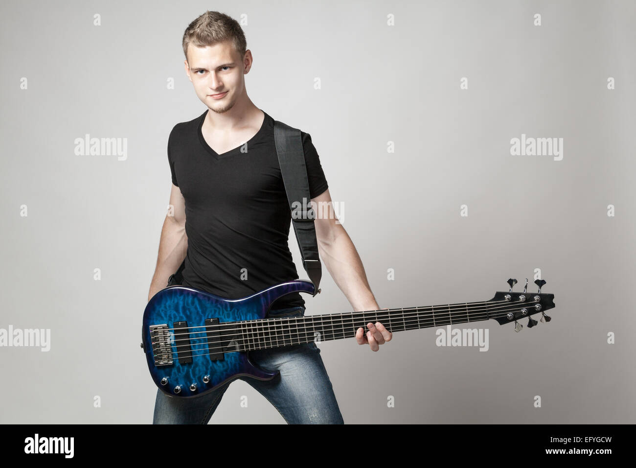 junge männliche Musiker mit 6-Saiter e-Bass auf hellem Hintergrund isoliert Stockfoto