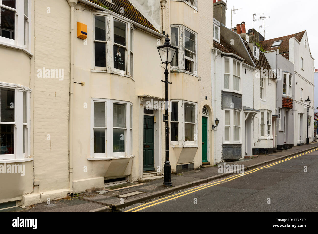Verkürzung des einen Laternenpfahl und eine Reihe der alten Hütten auf einer ansteigenden Straße in der touristischen Meer Stadt, Brighton, East Sussex Stockfoto