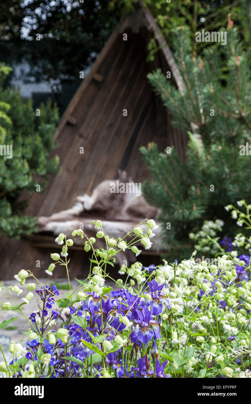 Garten-Sitzplatz eines Bootes, umgeben von Nadelbäumen und Wildblumen Stockfoto