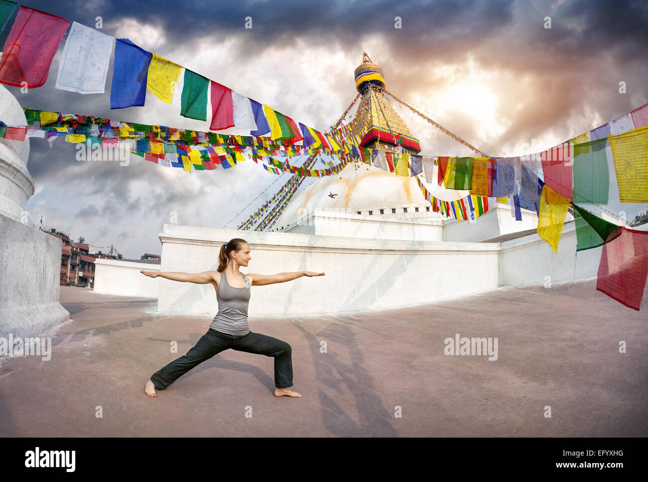 Frau tut Yoga-Krieger-Pose am Stupa Bodnath, Kathmandu, Nepal Stockfoto