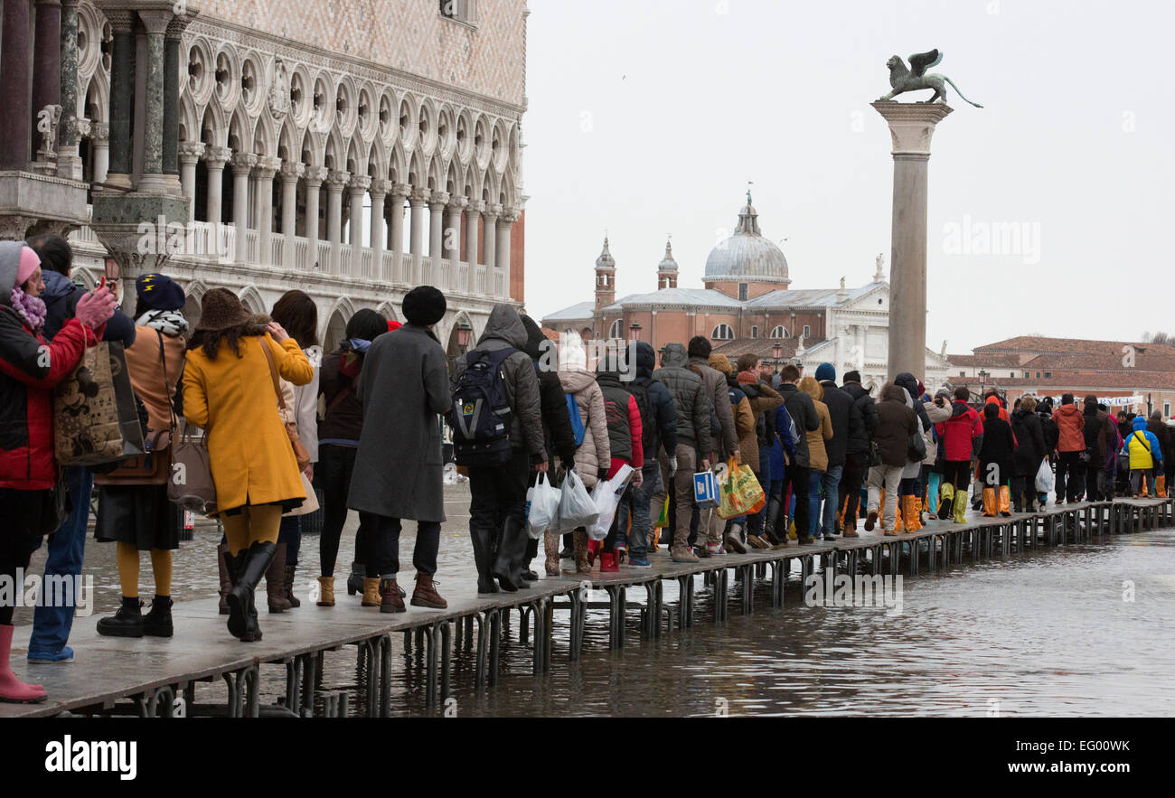 Im Bild: Touristen nutzen Gehwege, um trocken zu halten. Als der jährliche Karneval feiern losgehen, in Venedig, Hochwasser (Acqua Alta) viele Teile der Stadt überflutet. Viele Touristen wurden von den hohen Wassergehalt ertappt und musste kaufen verstärkten Kunststoff Stiefel in leuchtenden Farben - die über normale Schuhe - getragen werden, trocken zu halten. Besseres Wetter für den Karneval in Markusplatz entfernt dieses Wochenende prognostiziert. Stockfoto