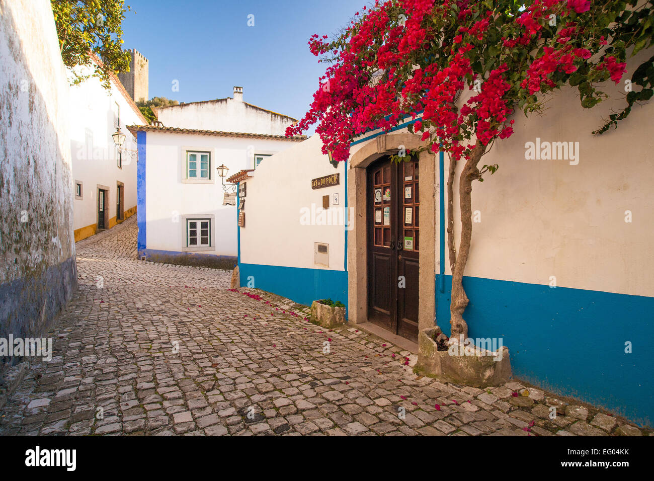 Typische gepflasterten Portugiesisch Straße in Obidos - weiße und blaue Wände mit hellen rosa Bougainvillea Stockfoto