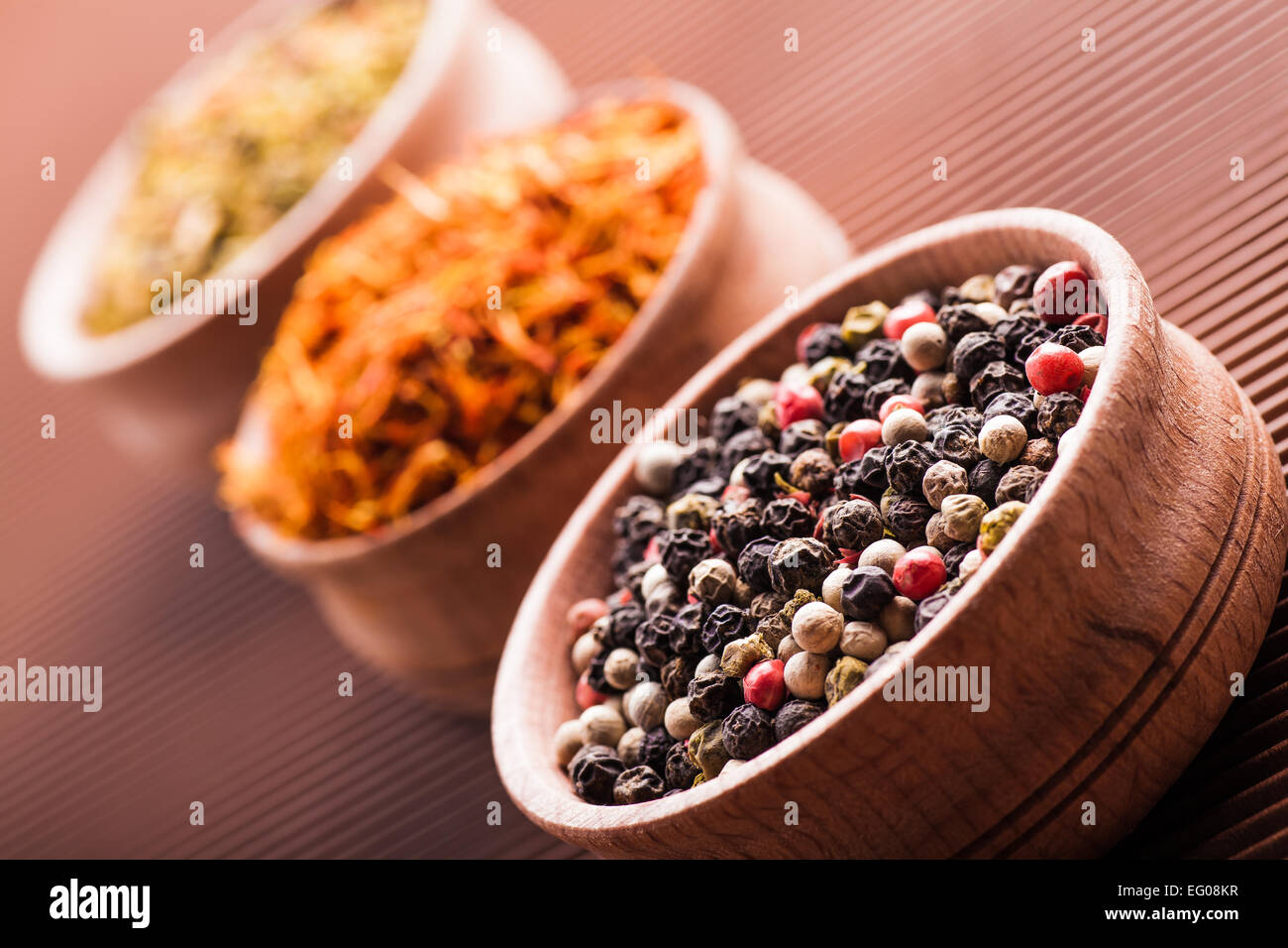 Gewürze Pfeffer, Safran, Paprika in einer Holzschale auf braunem Hintergrund Stockfoto