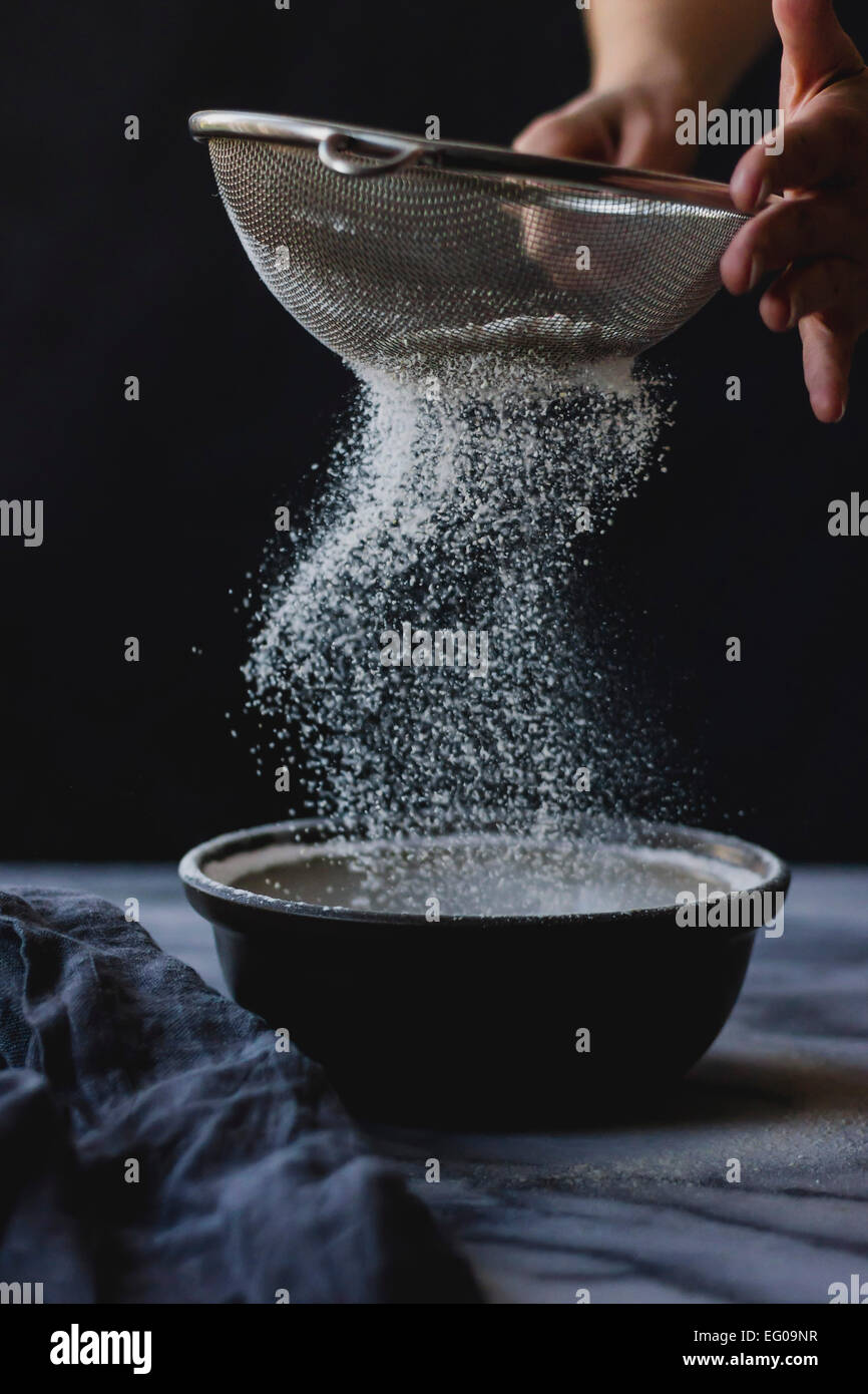 Mehl in eine Schüssel sieben, während Kochen Stockfoto