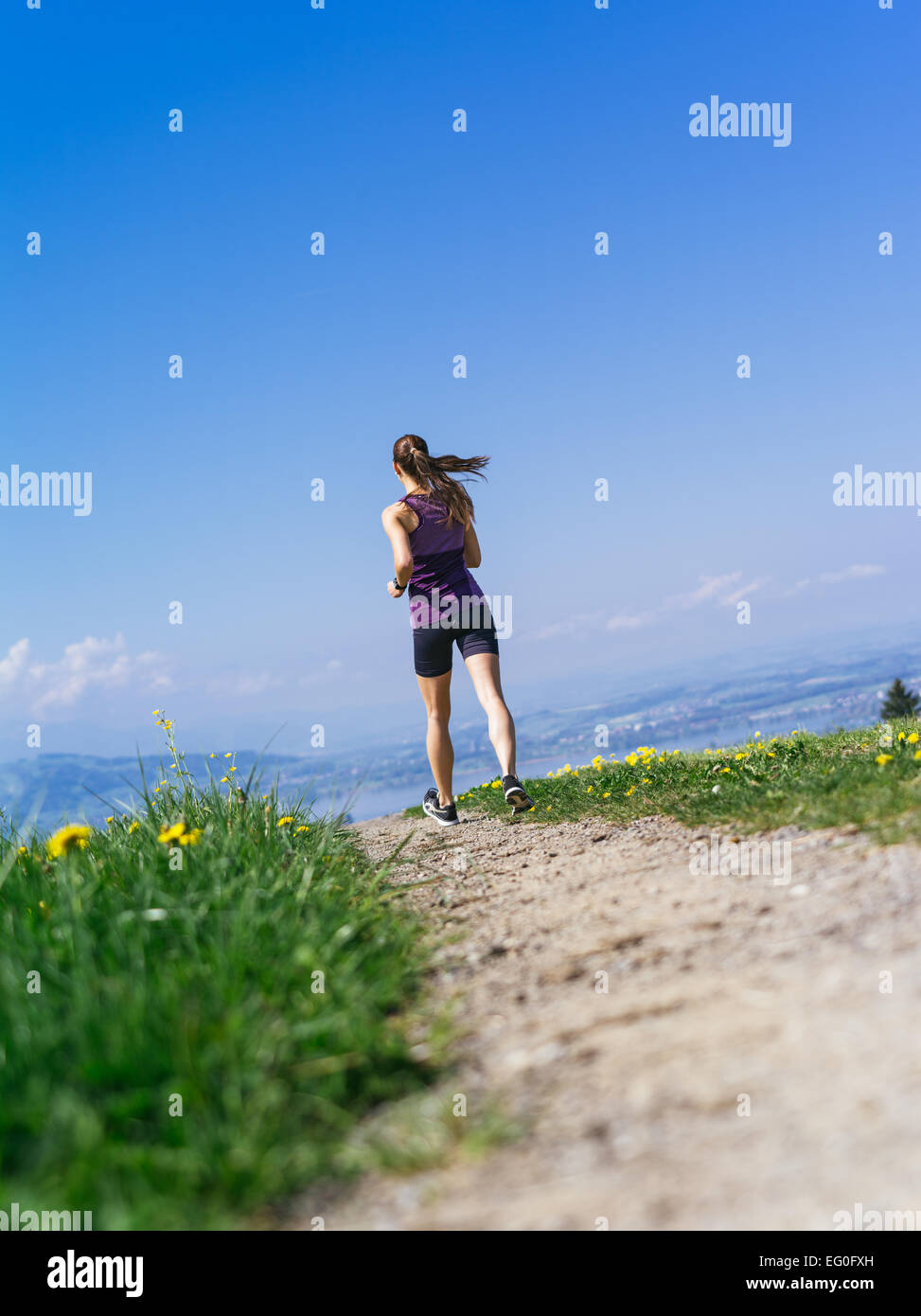 Foto einer jungen Frau, Joggen und trainieren auf einem Feldweg.  See in der Ferne. Stockfoto