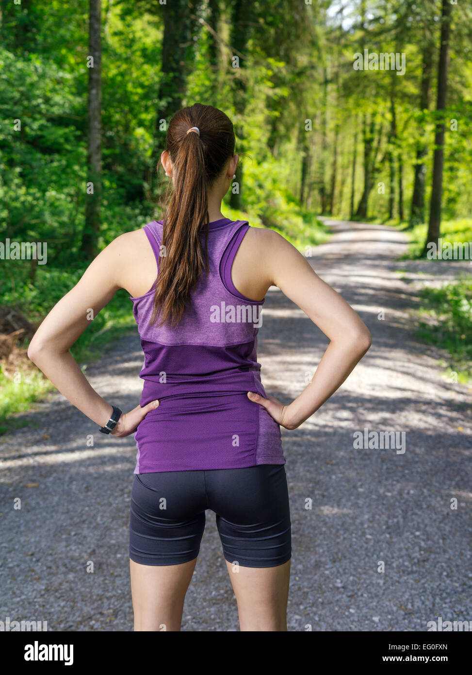 Foto einer jungen Frau blickte den Kiesweg durch einen Wald, bevor sie ihre Übung beginnt. Stockfoto