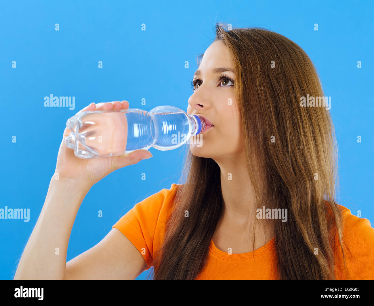 Foto von einer schönen jungen Brünette Frau in Flaschen abgefülltes Trinkwasser auf blauem Hintergrund. Stockfoto