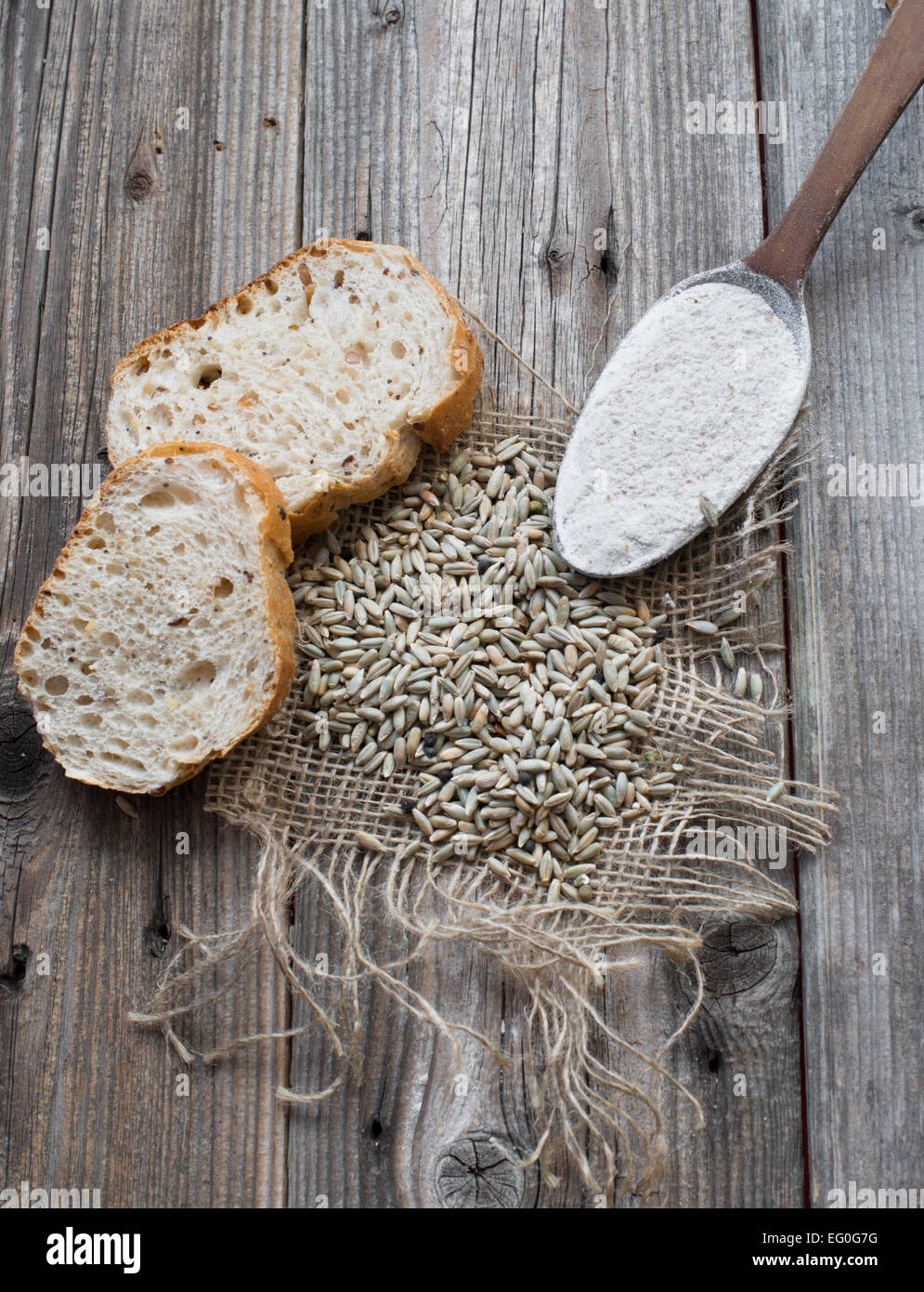 Roggen-Samen mit Scheiben Brot und Mehl in einem Holzlöffel Stockfoto