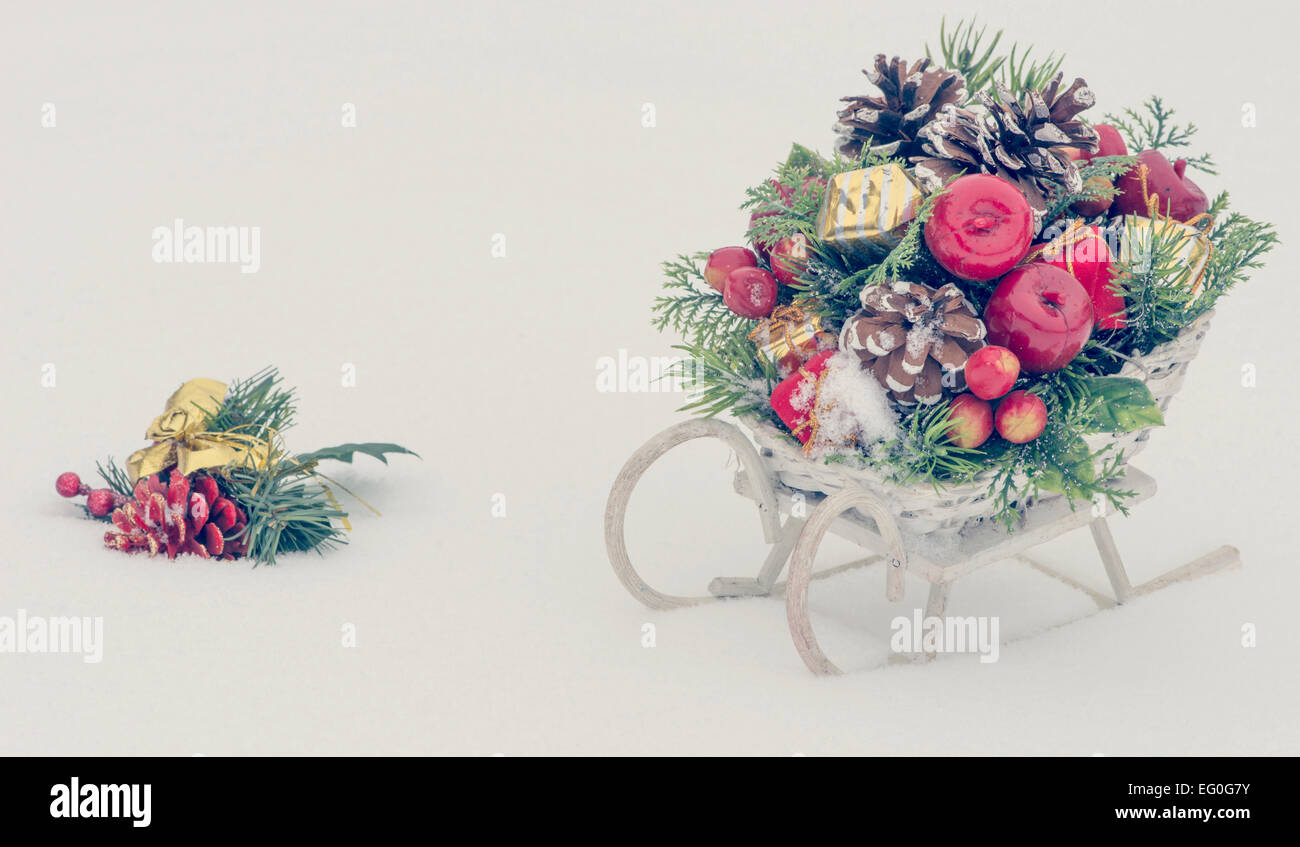 Holzspielzeug-Schlitten mit Weihnachtsdekoration auf verschneiten Hintergrund Stockfoto