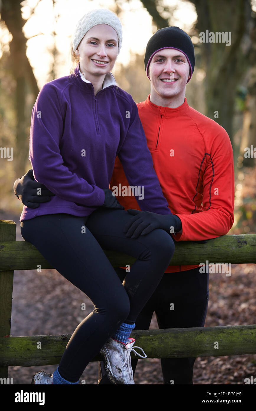 Porträt des Paares auf Winter Flucht durch den Wald auf Zaun sitzen Stockfoto