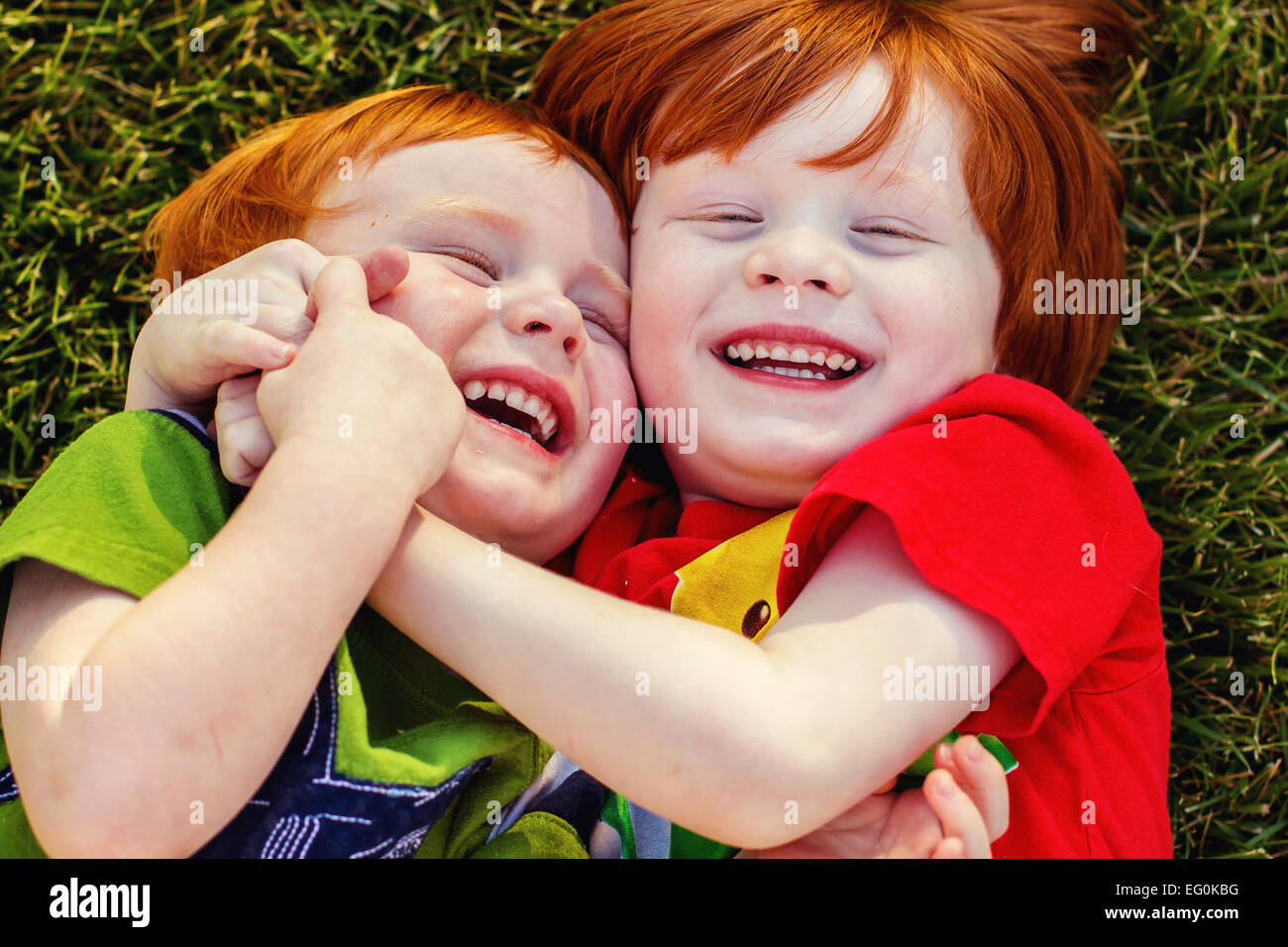 Zwei glückliche Jungs liegen auf Rasen vor Lachen Stockfoto
