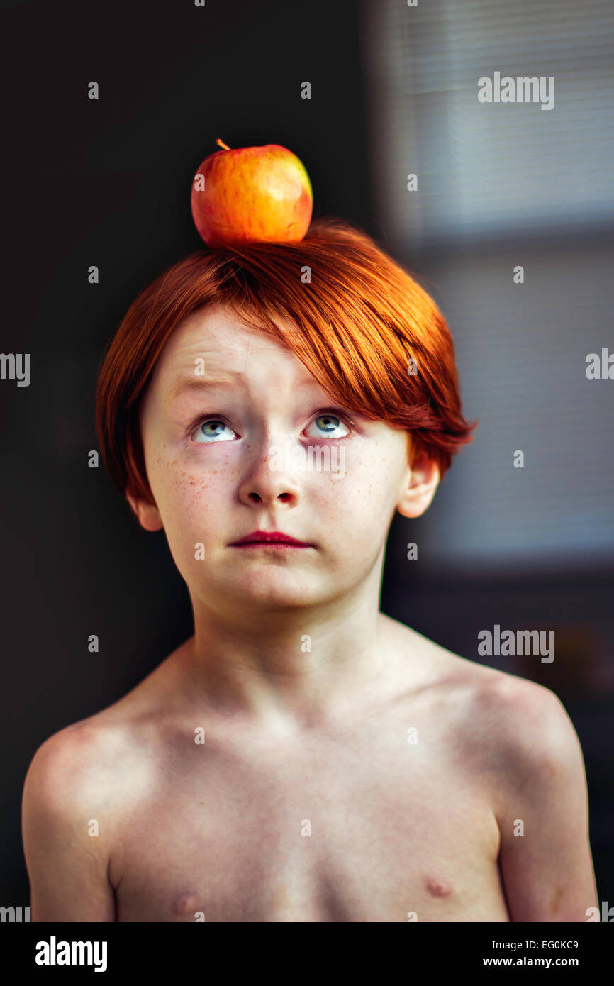 Junge, einen Apfel auf dem Kopf balancieren Stockfoto