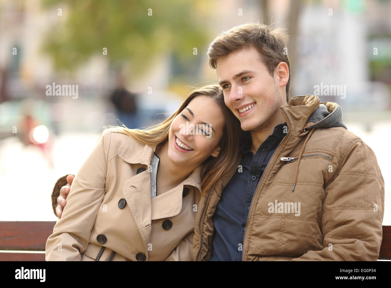 Paar in Liebe sitzen in einer Bank in einem städtischen Park im Winter umarmt Stockfoto