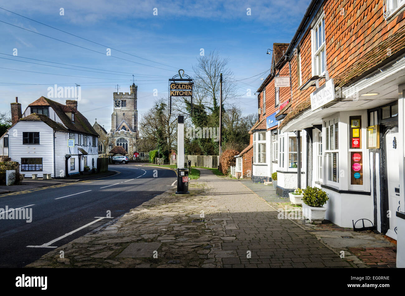 BIDDENDEN, Kent, UK, Januar 2015 - hohe Straße mit Kopfsteinpflaster, historische Gebäude und Kirche im Hintergrund Stockfoto