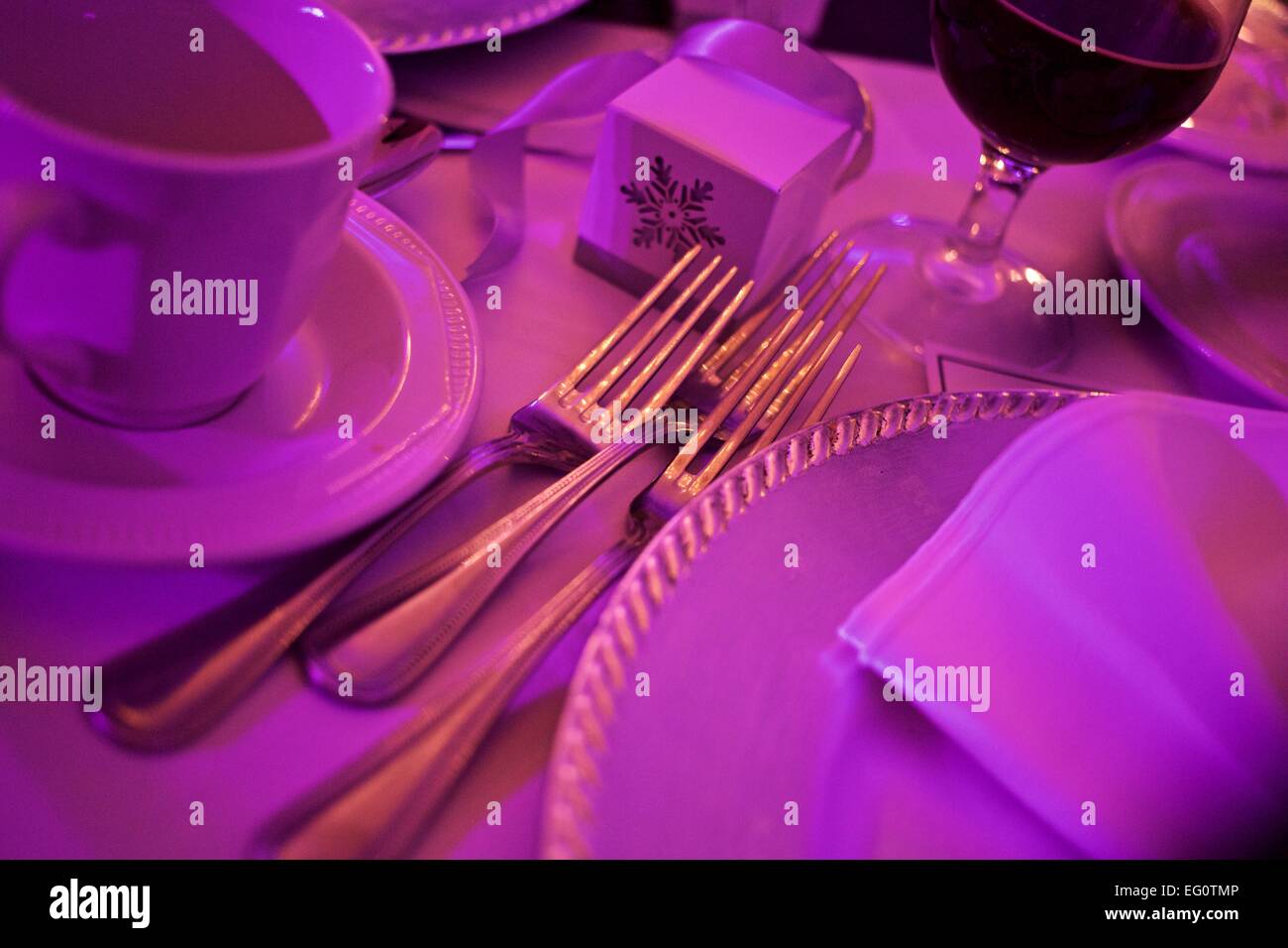 Tischdekoration bei einer Hochzeitsfeier mit Gabeln Tassen und Teller in lila Licht getaucht Stockfoto