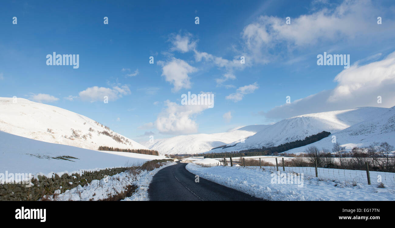 Leere Straße durch Schnee beklebt Hügel im Winter. Peebleshire, Scottish Borders, Schottland Stockfoto