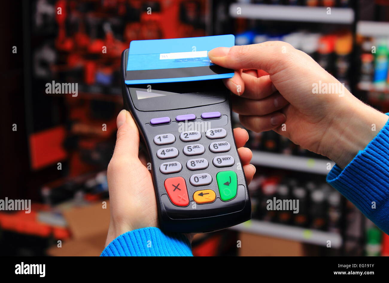 Hand der Frau bezahlen mit kontaktlosen Kreditkarte mit NFC-Technologie in einem Elektrofachgeschäft, Kreditkartenleser, Stockfoto
