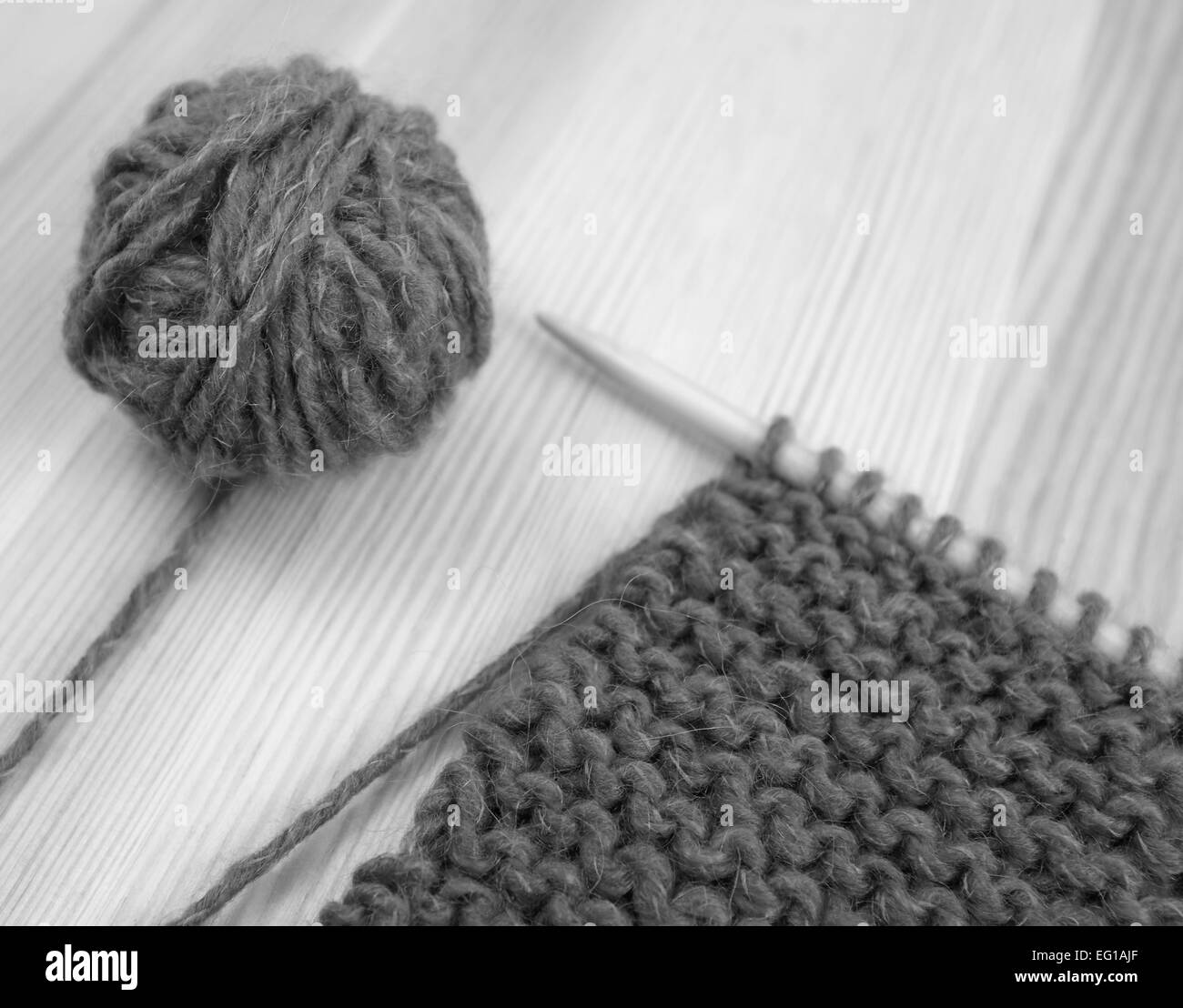 Nahaufnahme von Kraus rechts stricken auf der Nadel mit einem Ball aus Wolle - monochrome Verarbeitung Stockfoto