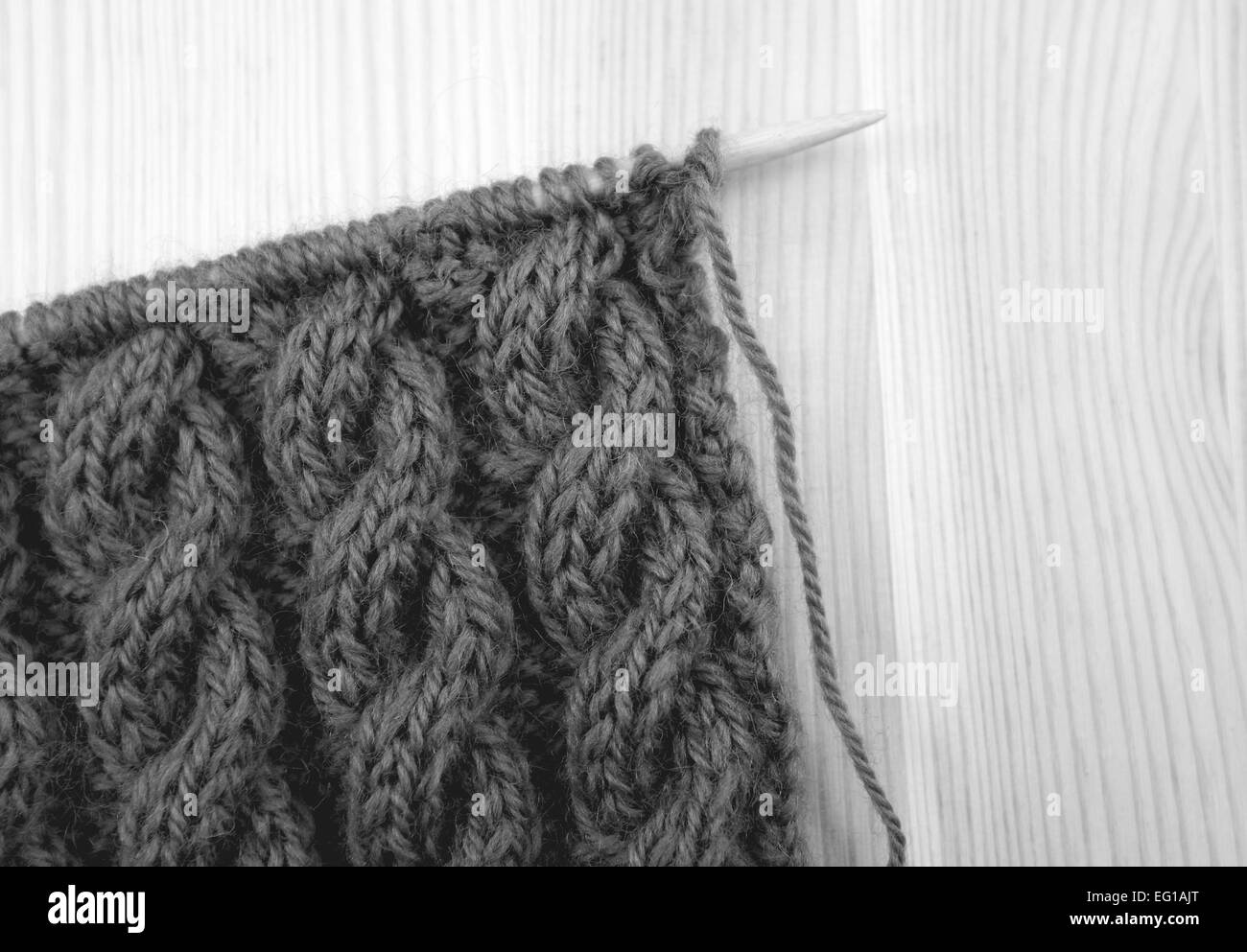 Gewickelte Seil Kabel stricken Masche auf der Nadel, auf einem hölzernen Hintergrund - monochrome Verarbeitung Stockfoto