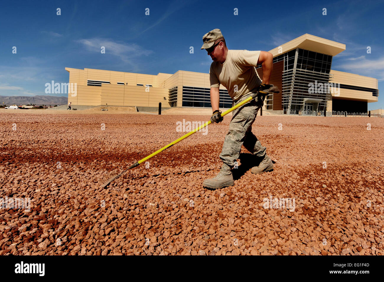 US Air Force Staff Sgt Chris Wright breitet sich Kies für ein Xeriscape-Design im neuen Krieger-Fitness-Center auf Nellis Air Force Base, Nevada, 20. März 2012.  Xeriscaping ist ein Weg, um Wasser zu sparen, indem Landschaftsbau in Möglichkeiten, die verringern oder beseitigen die Notwendigkeit, Wasser für die Bewässerung zu verwenden. Wright ist ein 99. Bauingenieur-Geschwader Pflaster und Bau Geselle.  Staff Sgt William P.Coleman Stockfoto
