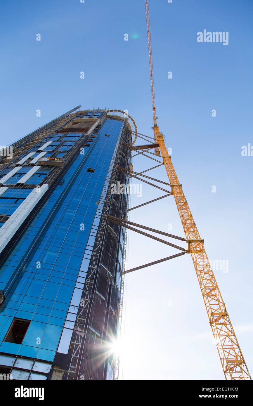 Riesiger Kran steigt in der Nähe von Bau eines Wolkenkratzers Stockfoto