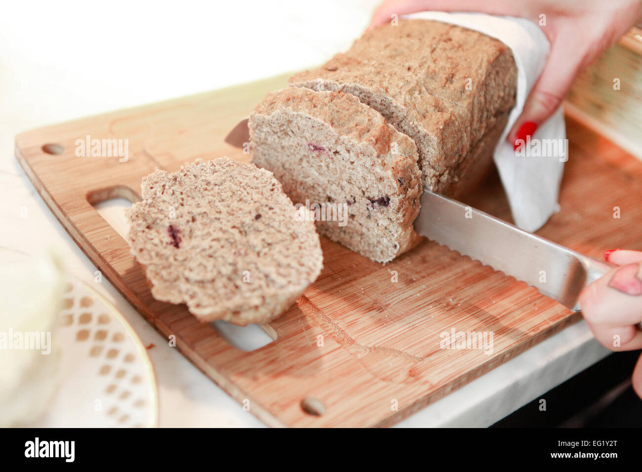 frisches Brot wird in Scheiben geschnitten auf einem Holzbrett Stockfoto