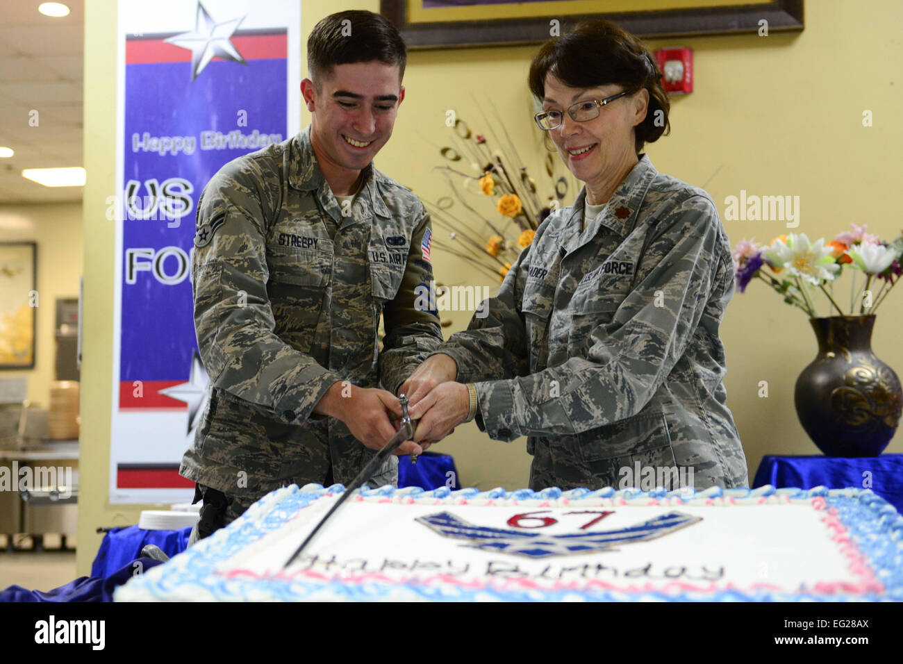 US Air Force Airman 1st Class James Streepy, 379th Expeditionary Sicherheit Kräfte Squadron, und Generalmajor Charlotta Leader, 379th Expeditionary Medical Operations Squadron Schneiden der Luftwaffe Geburtstag Kuchen auf Al Udeid Air Base, Katar, 18. September 2014. Führend ist der 379th Air Expeditionary Wing älteste Airman, sie wurde 1952 geboren und in der Air Force Reserve im Jahr 1986 in Betrieb genommen. Streepy war des Flügels des jüngsten 1995 geboren, trat er August 2013.  Staff Sgt Ciara Wymbs Stockfoto