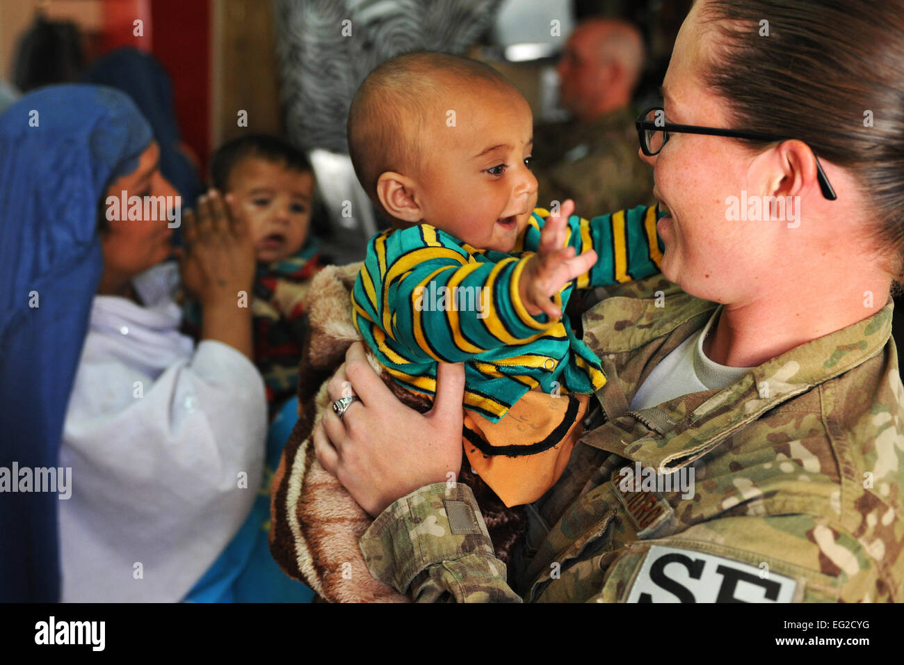 Flieger 1. Klasse Riostasia Johns, 455. Expeditionary Sicherheit Kräfte Squadron Eintrag Controller, hält einen lokalen afghanischen Baby während ihrer Mutter-Prozesse durch die medizinische Eingangskontrolle auf Bagram Airfield, Afghanistan, am 16. April zeigen.  Senior Airman Chris Willis Stockfoto