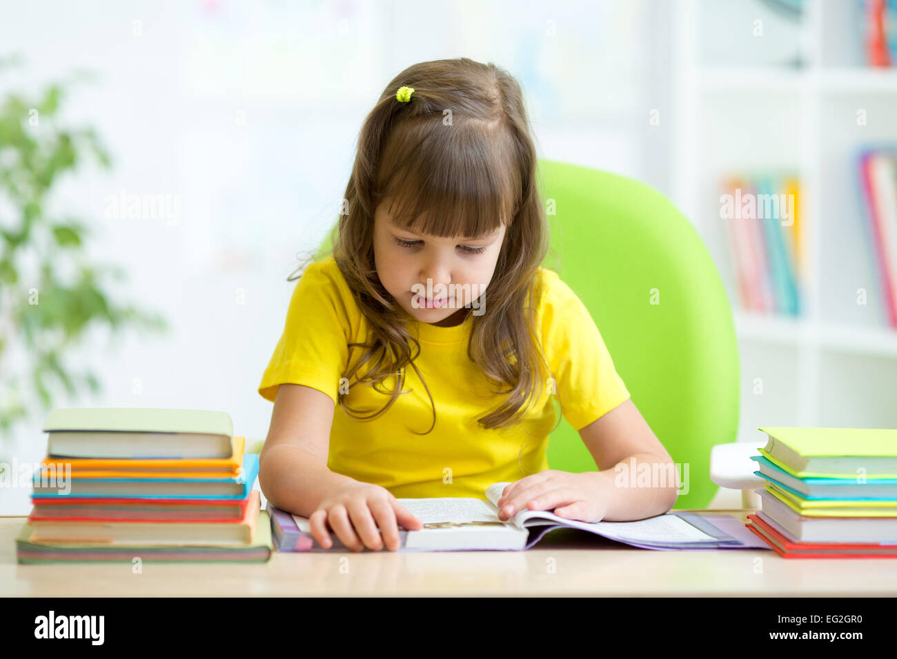 Süßes Kind Mädchen lesen Geschichte aus Buch im Kindergarten Stockfoto