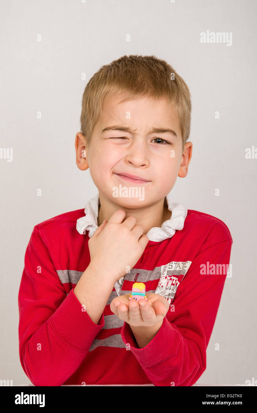 Sechs Jahre alten Jungen kämpfen, um wink, Nachahmung seiner Shopkins Spielzeug, das Zwinkern ist Stockfoto
