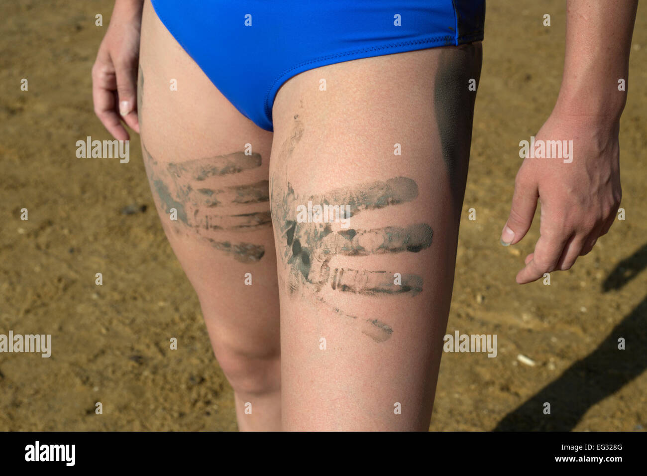 Junge Frau mit Schlamm Palm druckt auf ihre Beine Modell veröffentlicht Stockfoto