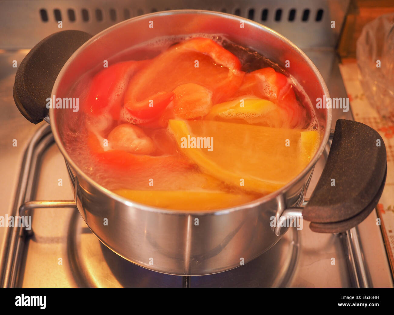 Gelbe und rote Paprika Gemüse gesunde vegetarische Küche Essen in einem Saucepot auf Gasherd Stockfoto