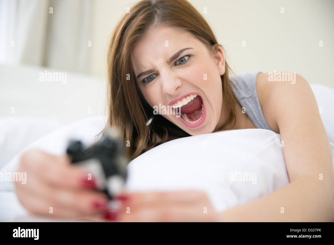 Böse Frau, die sehr früh aufgewacht, rufen Sie einen Wecker im Schlafzimmer Stockfoto
