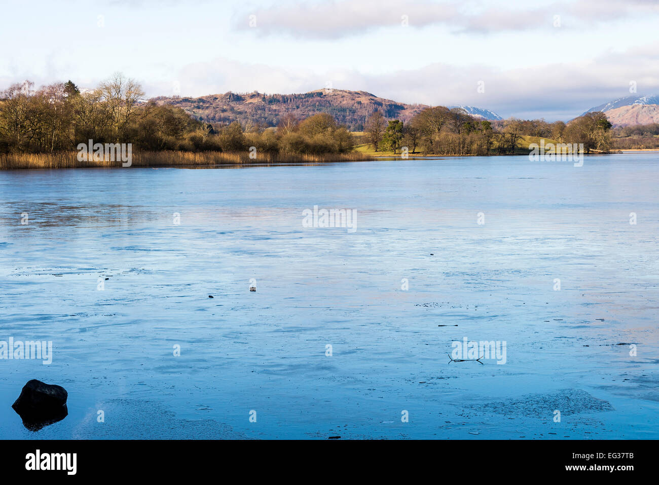 Eine dünne Schicht von Eis bedeckt Esthwaite Wasser mit den Lakeland-Hügeln im Hintergrund auf einen Winter Tag Seenplatte Cumbria England Stockfoto