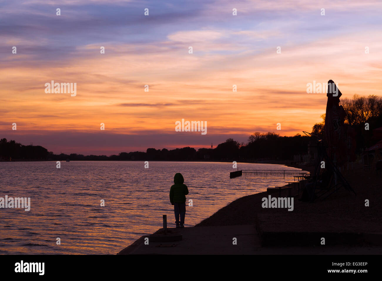 Sonnenuntergang fällt auf dem See bei Ada Ciganlija in Belgrad Serbien. ein Kind blickt vom Ufer entfernt. Mehr Beograda oder Belgrads Meer Stockfoto